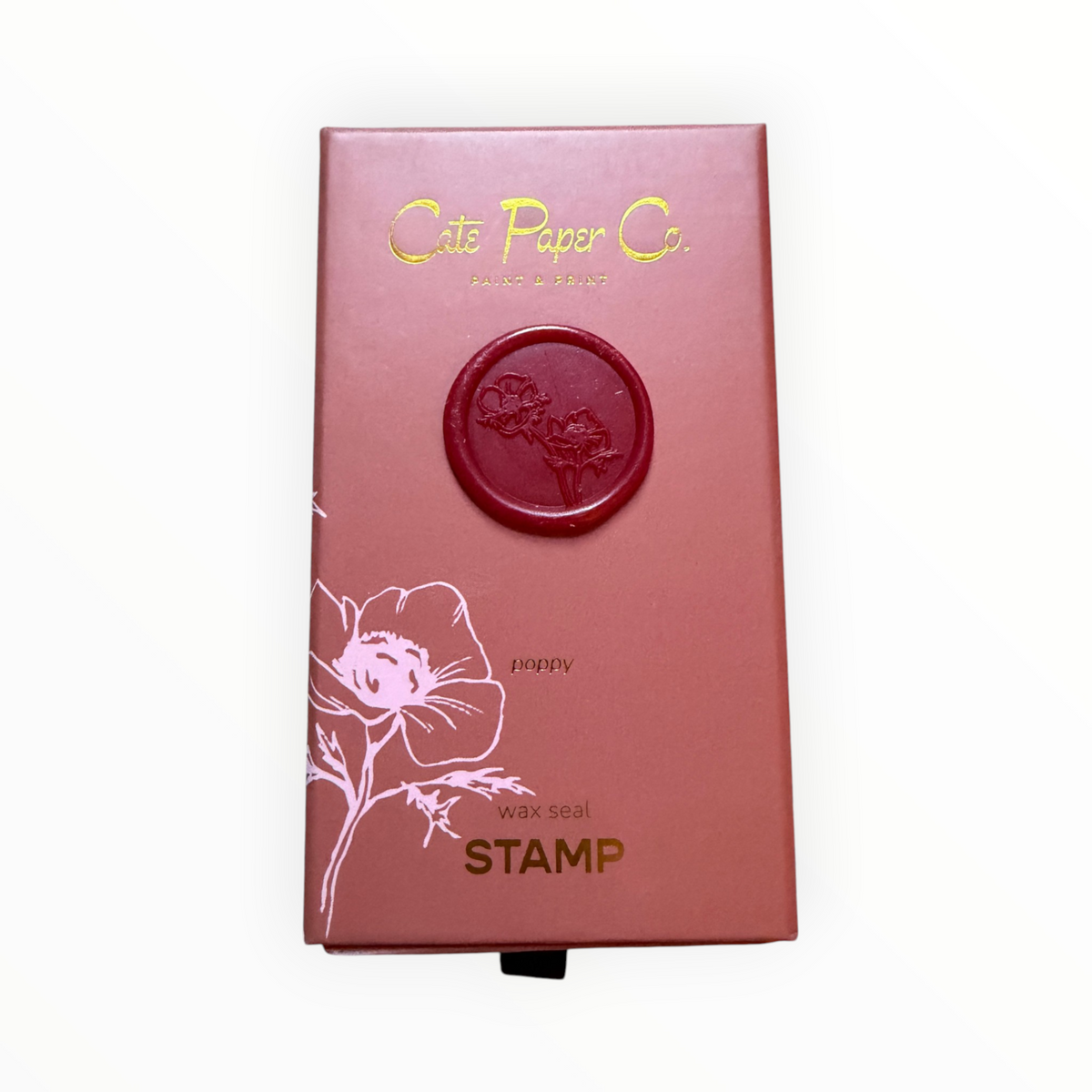 A rectangular pinkish-red box for a Cate Paper Co. wax seal stamp, featuring a circular embossed red wax seal on the front, gold foil branding, and a white floral line drawing, photographed on a clean white background.