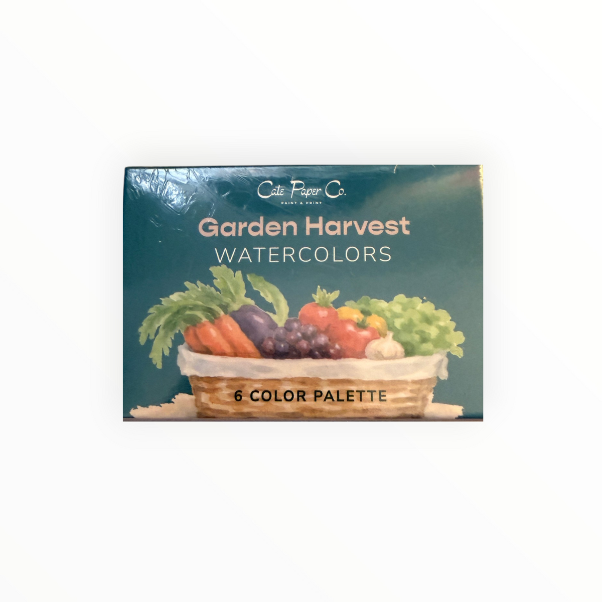 A boxed watercolor palette titled 'Garden Harvest' by Cate Paper Co., featuring a teal cover with an illustration of a basket of vegetables and fruit.