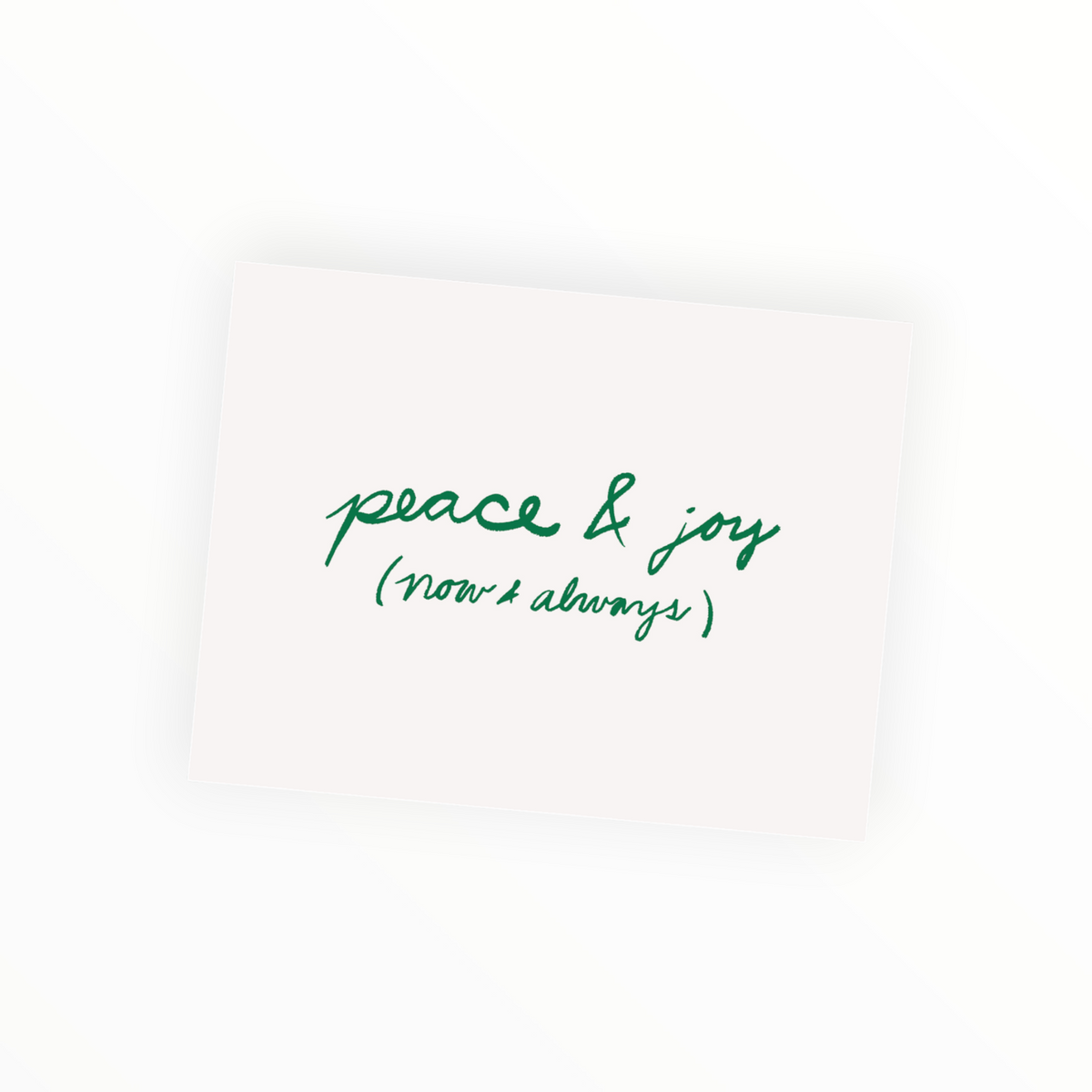 A square cream-colored card with green cursive text reading 'peace & joy (now & always)' on a clean white background.