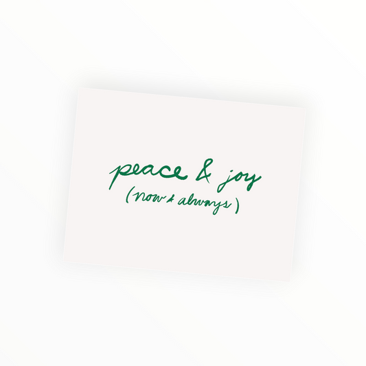 A square cream-colored card with green cursive text reading 'peace & joy (now & always)' on a clean white background.