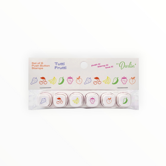A set of six fruit-themed push button stamps in their original packaging, featuring illustrations of grapes, cherries, bananas, strawberries, peaches, and peppers on a white background. Tutti Frutti stamps by brand My Darlin'.
